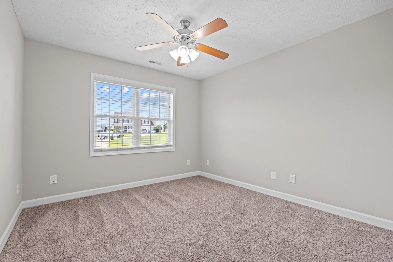 Bright bedroom with new carpet, fresh paint and a ceiling fan