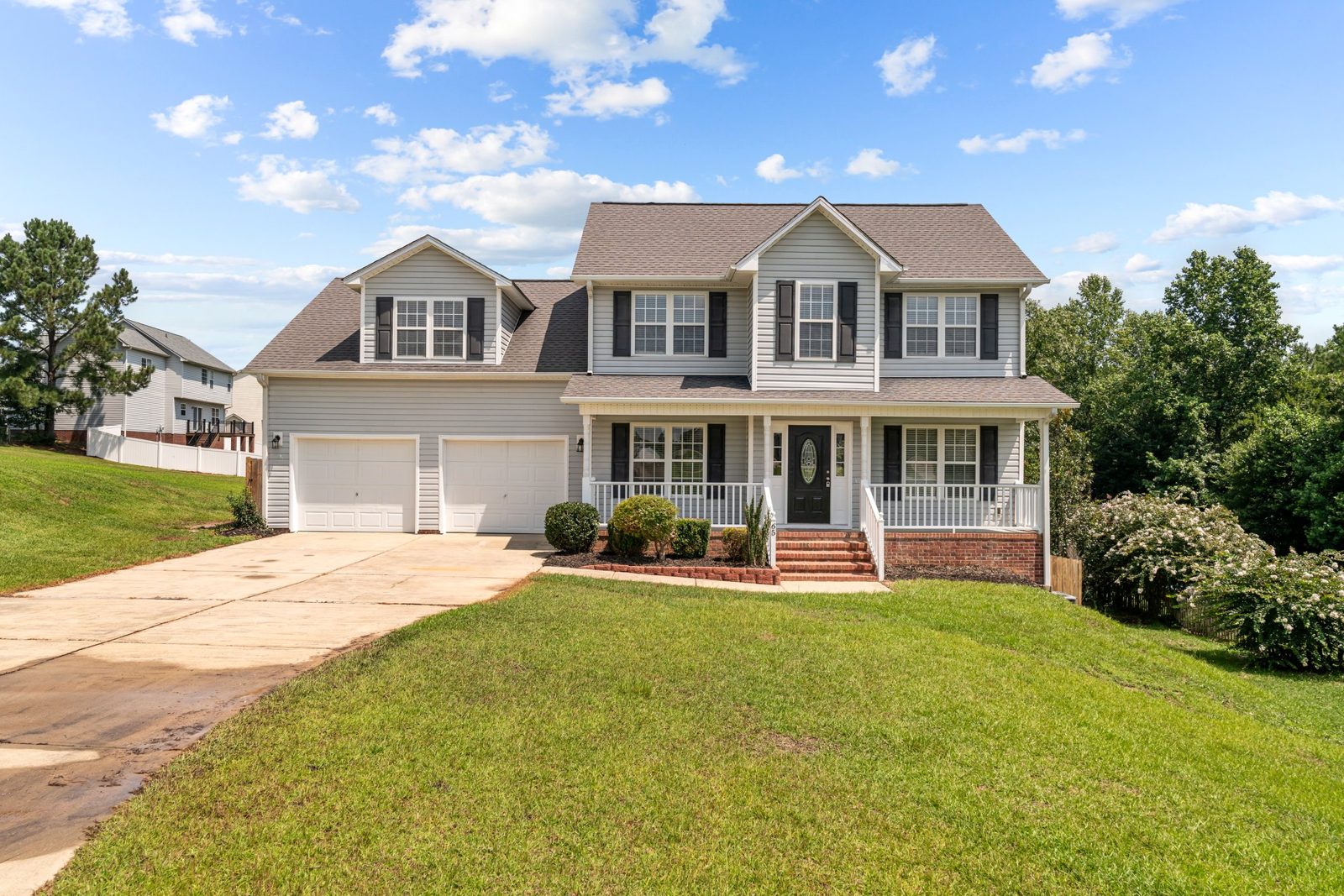 Front view of a two-story home with a refreshed shingle roof and wide driveway