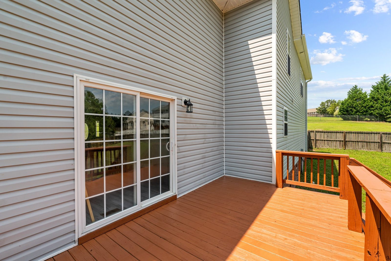 Rear deck with a sliding glass door on a home with gray siding