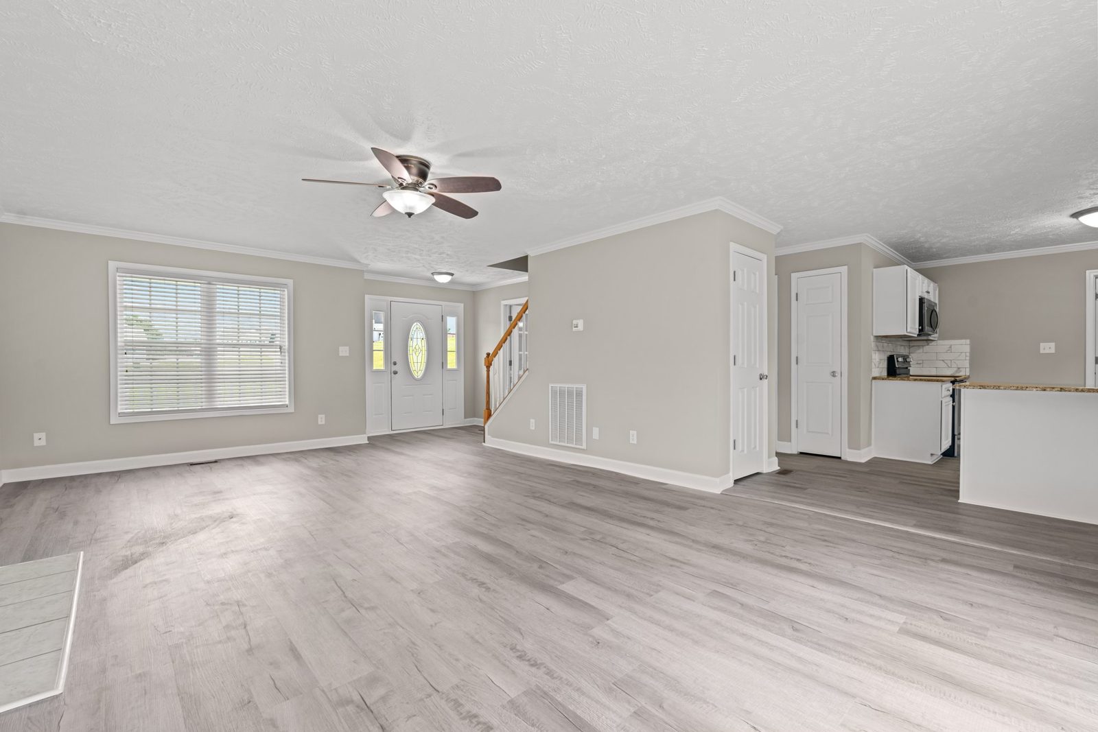 Open living area with new gray plank flooring leading to the stairs