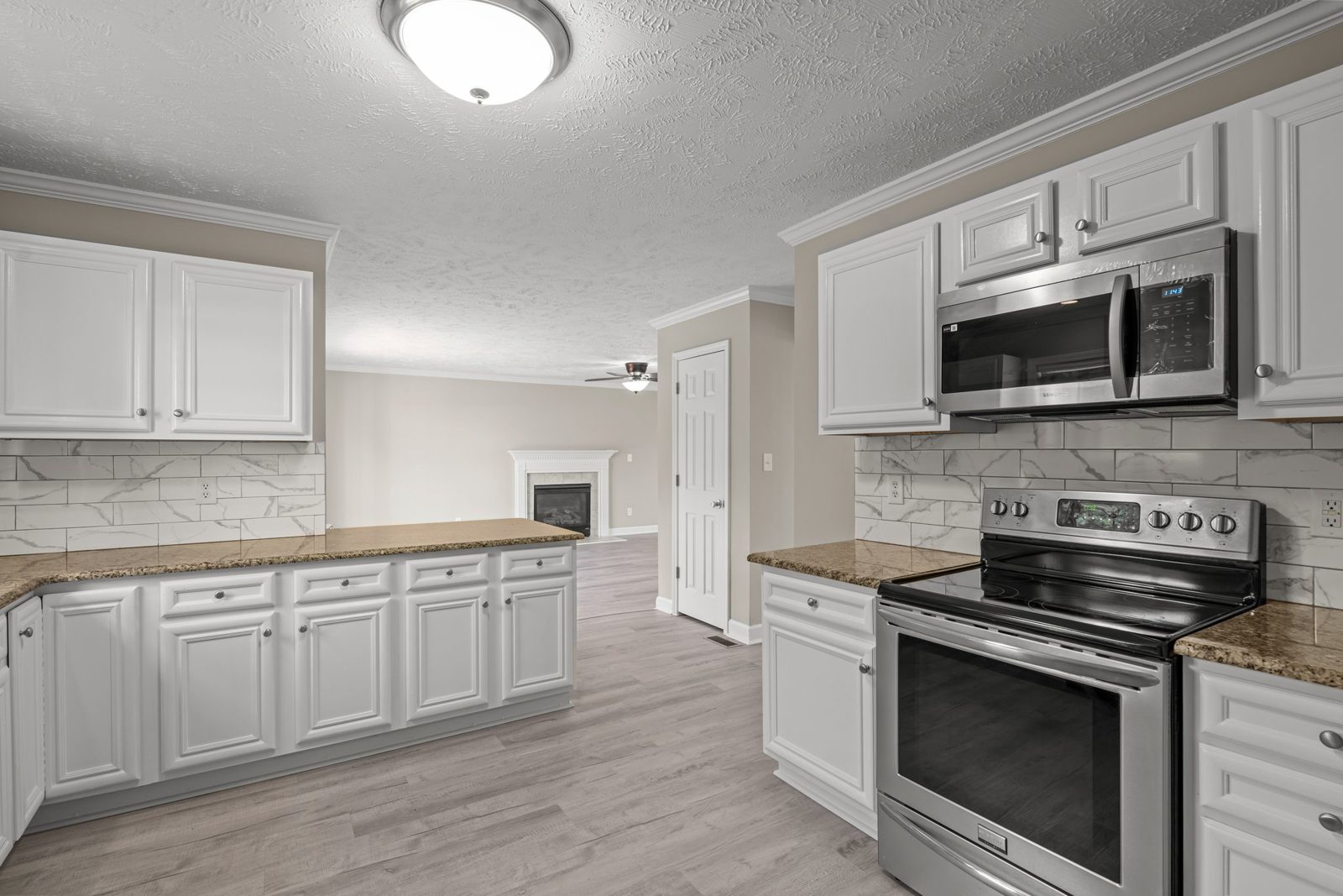Kitchen with white cabinets, tile backsplash and a stainless range