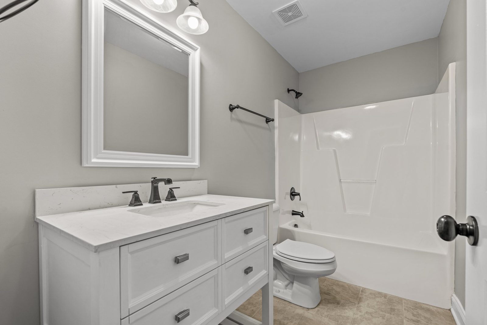 Hall bathroom with a white vanity, black fixtures and tub with shower