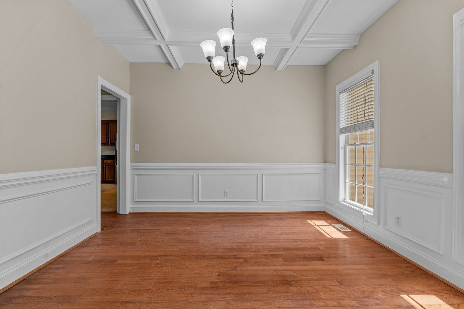 Dining room with refinished wood floors, wainscoting and chandelier