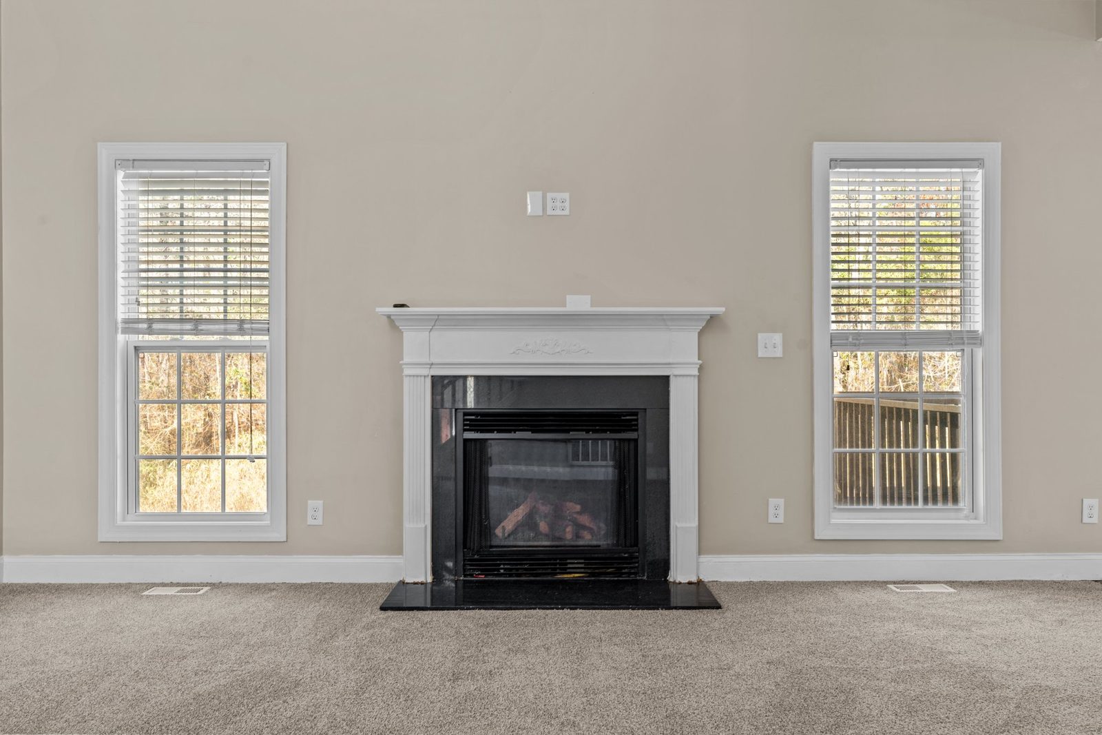 Living room with new carpet and a black fireplace with a white mantel