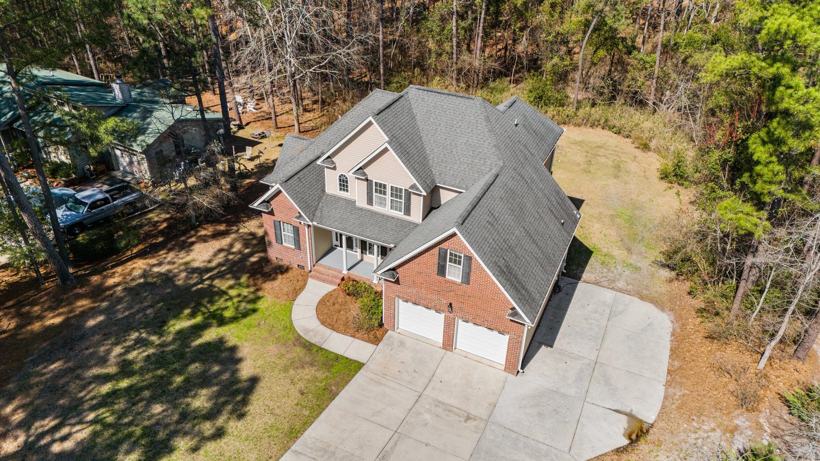 Drone view of a brick home with a full roof replacement in gray shingles