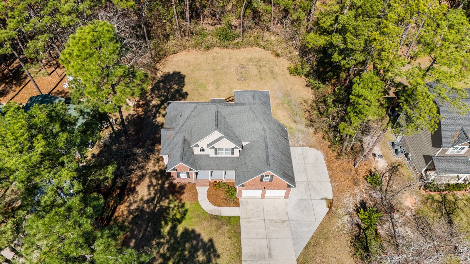 Overhead drone view of a new gray shingle roof on a wooded lot