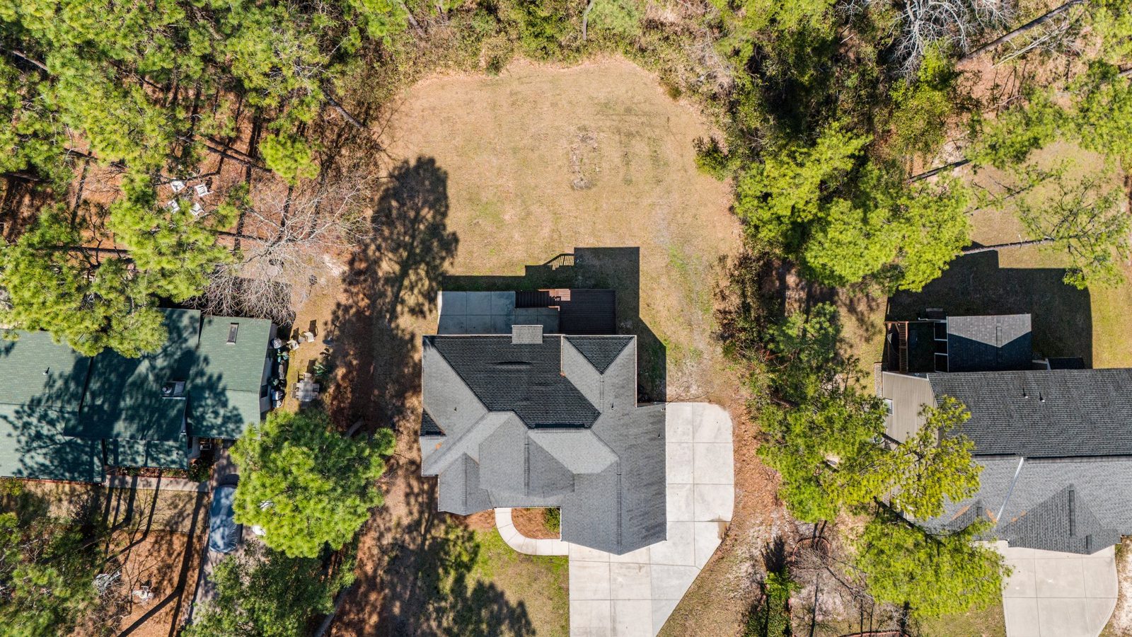 Drone view from above of a new shingle roof among pine trees