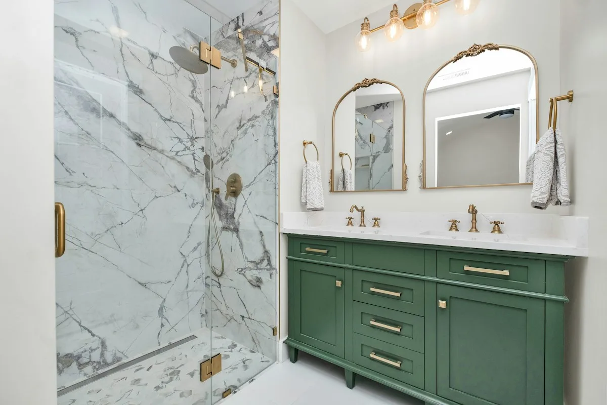 Bathroom with green cabinets and a marble shower