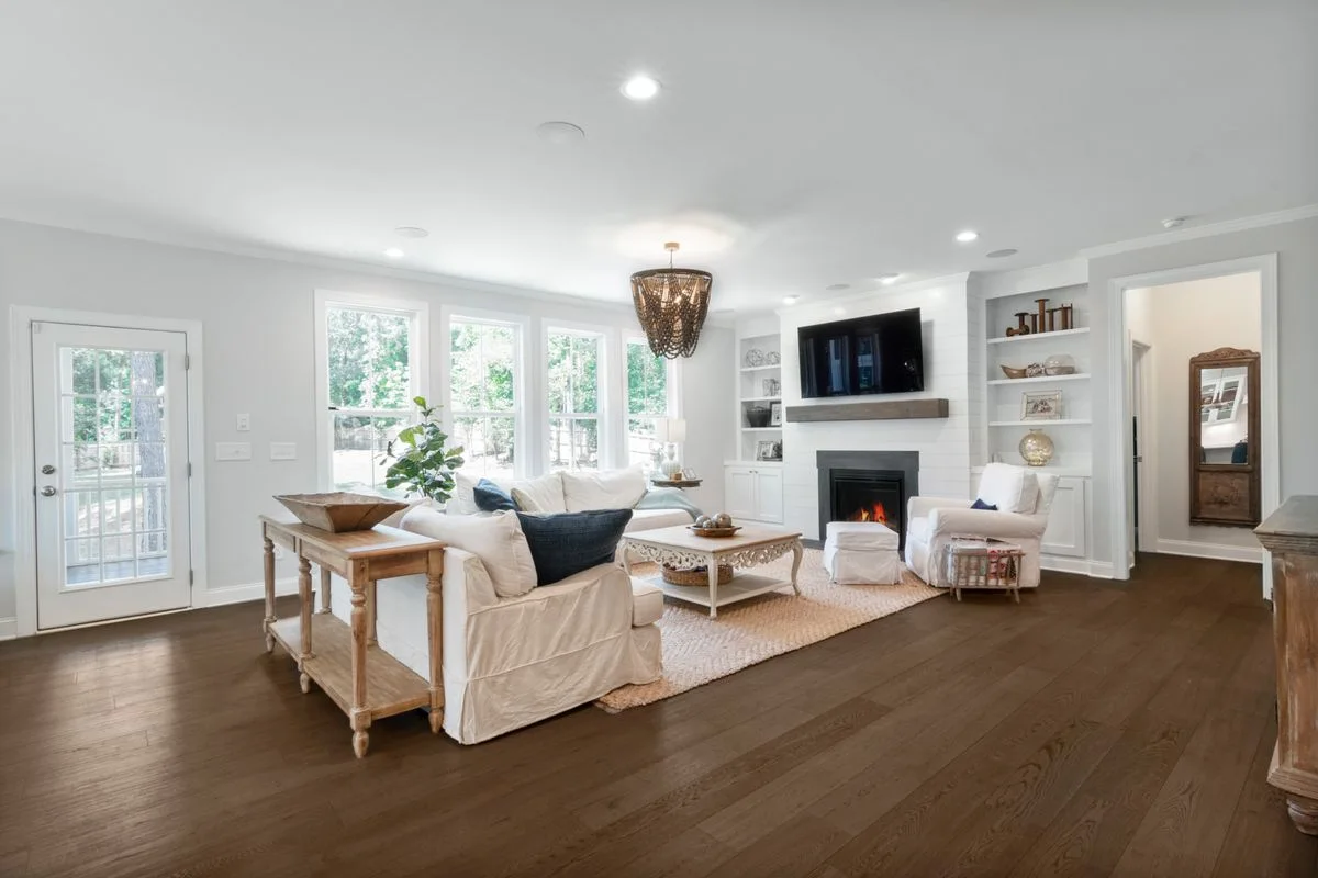 Bright family room with a fireplace, white sofas and wood floors