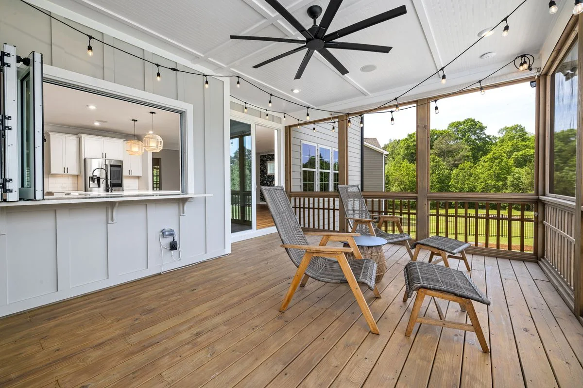 Screened porch with a wood floor, ceiling fan and lounge chairs