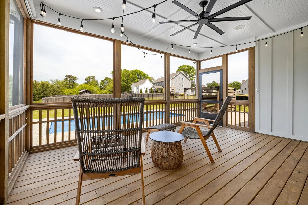 Screened porch with wood chairs overlooking a backyard pool