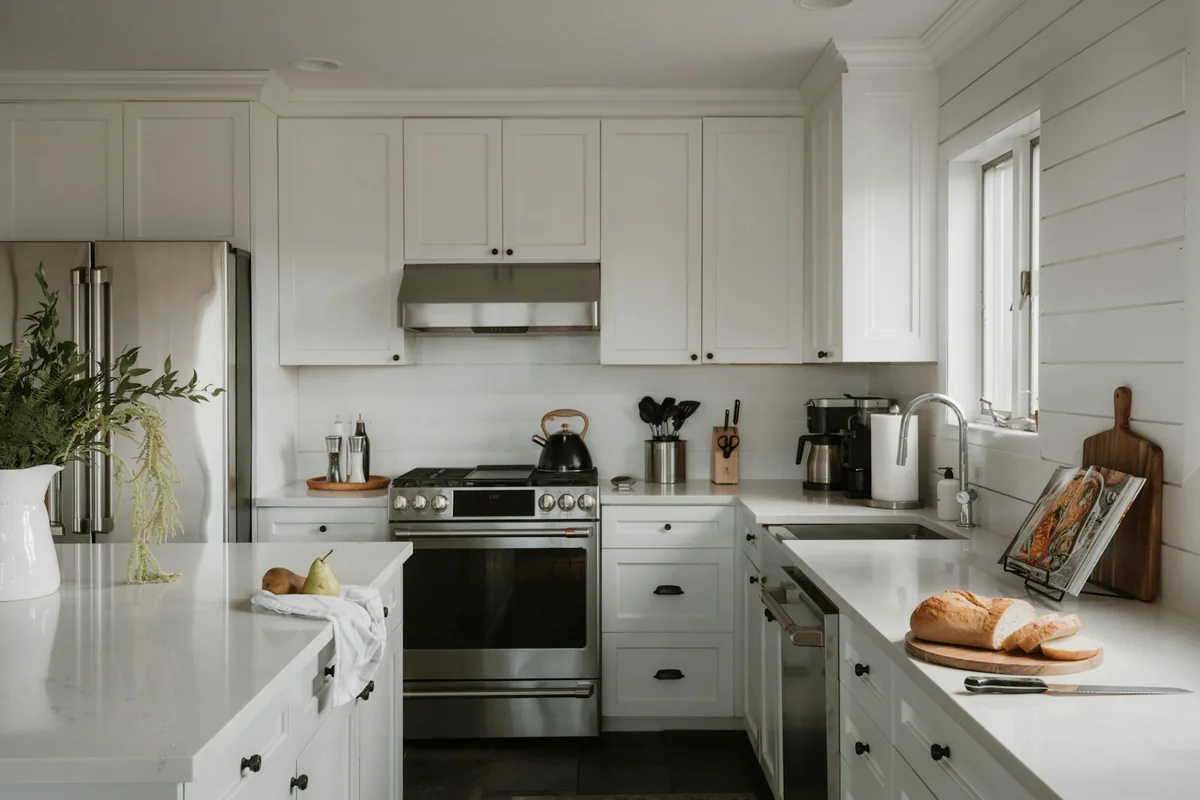 White farmhouse kitchen with shaker cabinets and stainless range