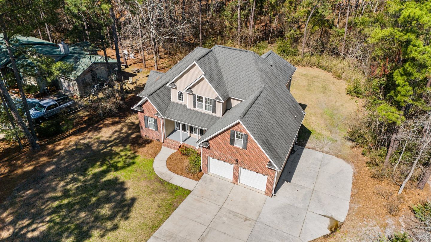 Drone view of a brick and siding home in Sanford, NC after a full roof replacement by Red Wolf Roofing & Construction